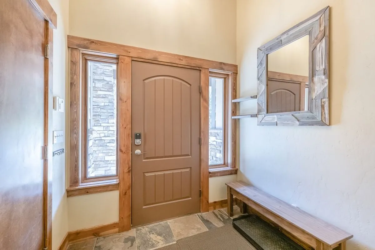 This image showcases the home's entryway, featuring a front door, windows, a mirror, and a bench—perfect for putting on shoes and storing outdoor gear before heading out for an adventure. The inviting space captures the moments when guests arrive or prepare for the day.