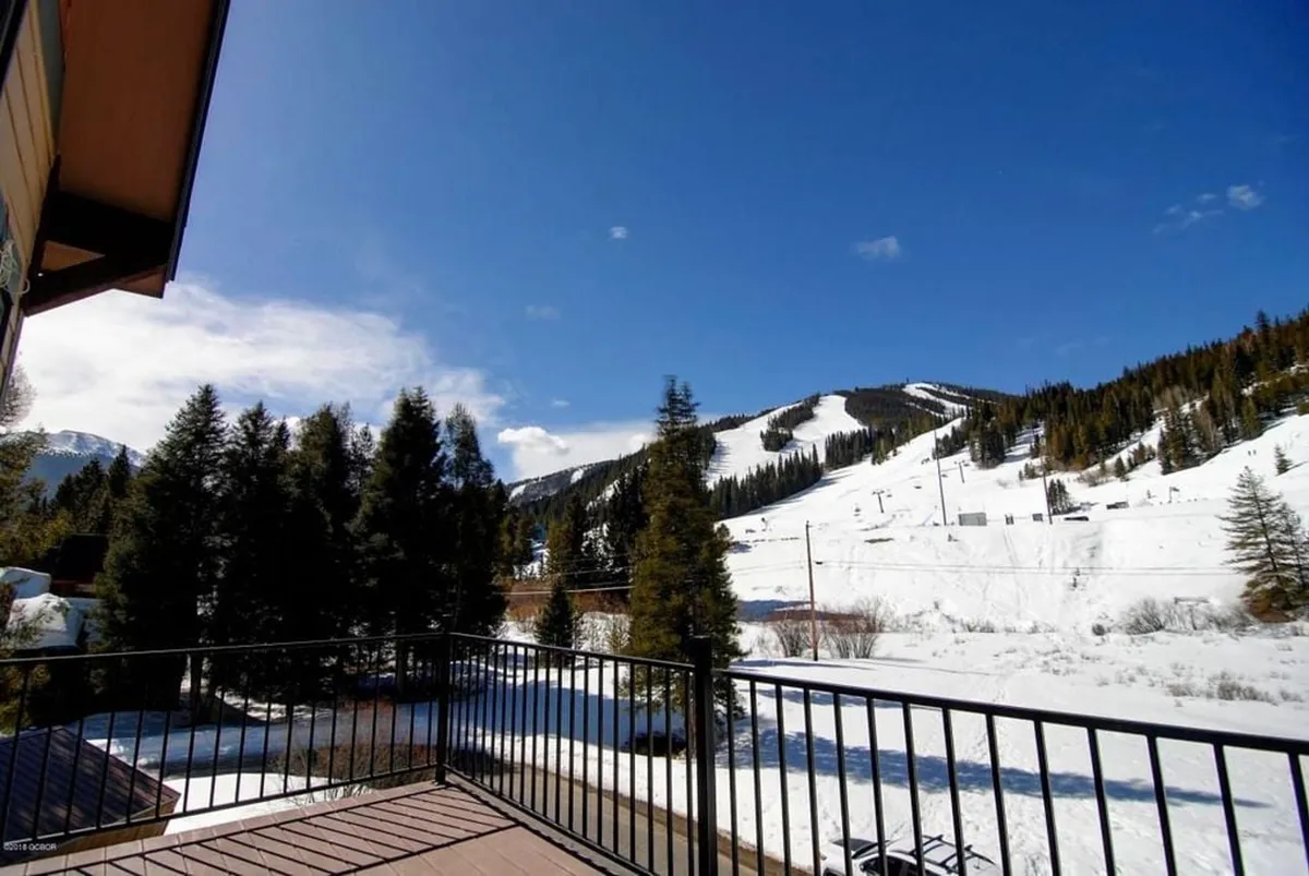 An exterior view of snow-capped mountains and dense pine forests under a clear blue sky, hinting at the tranquil beauty and vastness of the area. The image suggests opportunities for skiing, snowboarding, hiking, and nature walks—activities available during the winter season.