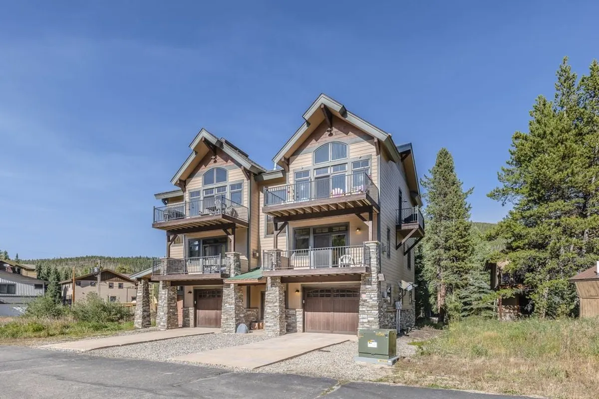 An inviting exterior shot of Villa 136 and neighboring two-story homes, featuring stone accents and balconies. The outdoor setting suggests a welcoming environment for gatherings, with ample space for children to play and families to socialize.